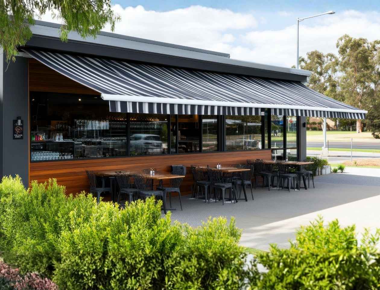 Toldo tapasol con franjas blancas y negras sobre terraza con mesas en restaurante contemporáneo
