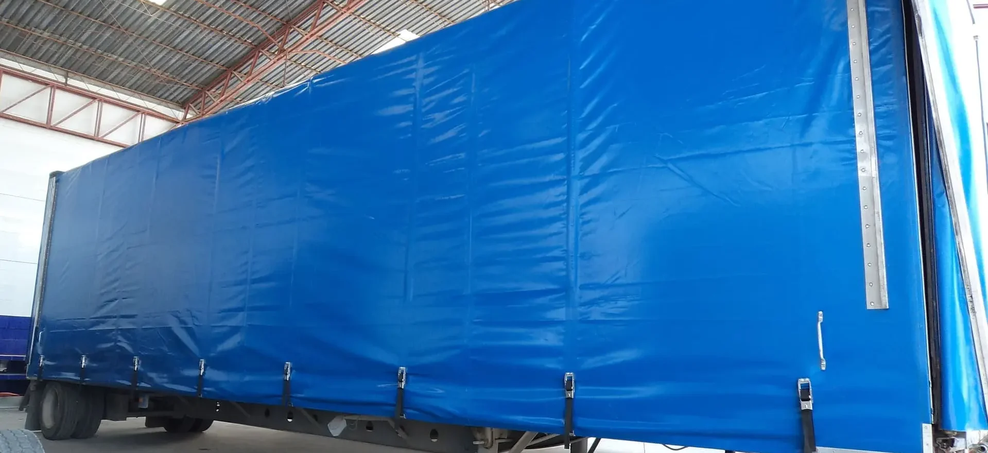 Lona reforzada con ojillos y costuras resistentes para uso industrial