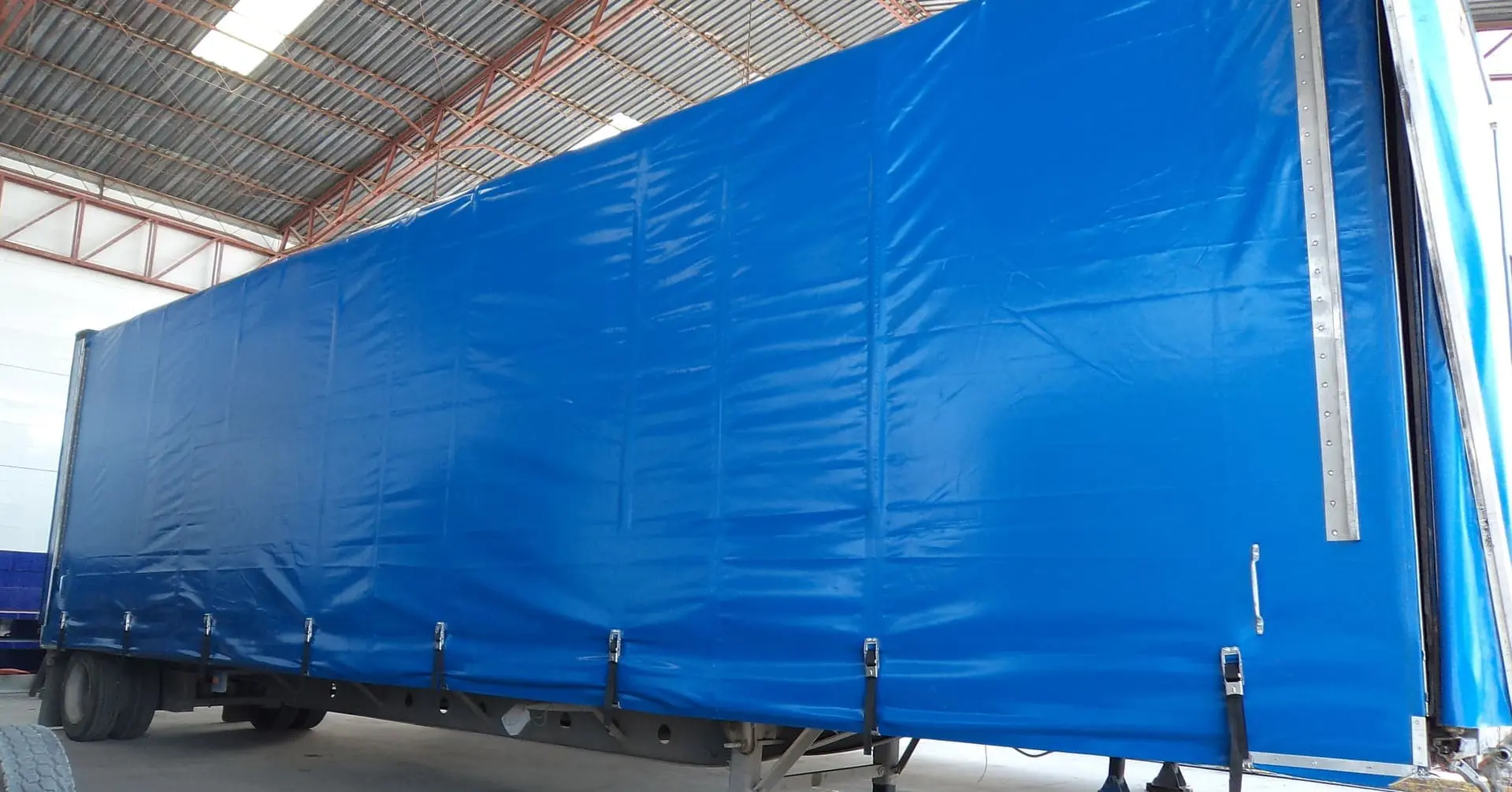 Lona reforzada con ojillos y costuras resistentes para uso industrial