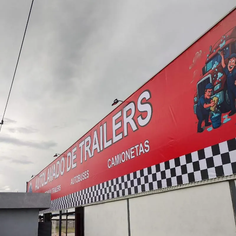 Fachada comercial con lona roja de gran formato y texto “TRAILERS”, ejemplo de anuncio en lona.